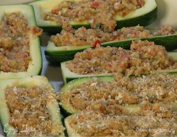 Лодочки цукини выложить в жаропрочную форму, наполнить выемки фаршем, посыпать сверху оставшимися панировочными сухарями, полить оливковым маслом и присыпать сыром.
