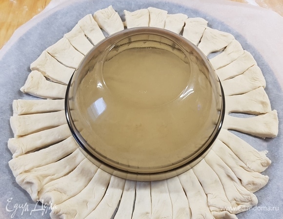 Поднявшееся тесто раскатать в круг. В середину поставить салатник — это будет центр. Вокруг тесто разрезать на полоски.