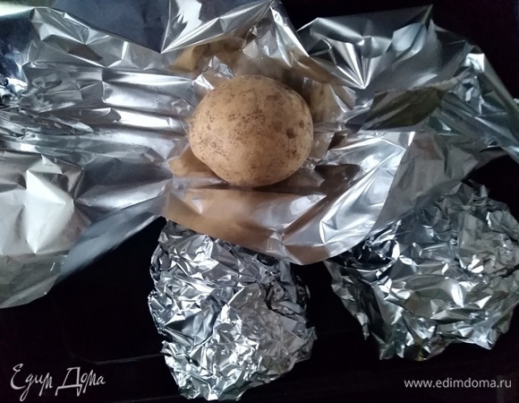Картофель лучше взять среднего размера. Хорошо его вымыть при помощи щетки. Смазать маслом фольгу, завернуть в нее картофель в кожуре и запекать в духовке около 45–50 минут. Духовку не выключать.