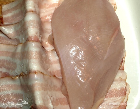 Курицу промыть, просушить бумажными полотенцами. Кладем мясо на бекон, делаем надрез вдоль филе, солим.