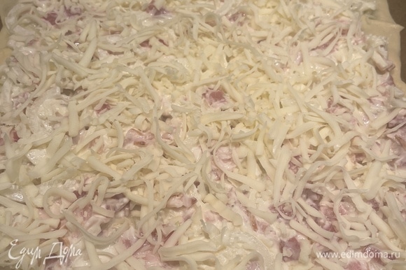 Раскатываем тесто в тонкий прямоугольник на бумаге, выкладываем начинку и посыпаем сверху оставшимся сыром. Запекаем в духовке, разогретой до 200°C, 20–25 минут, до образования красивой корочки.