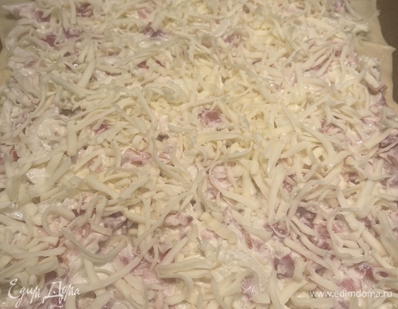 Раскатываем тесто в тонкий прямоугольник на бумаге, выкладываем начинку и посыпаем сверху оставшимся сыром. Запекаем в духовке, разогретой до 200°C, 20–25 минут, до образования красивой корочки.