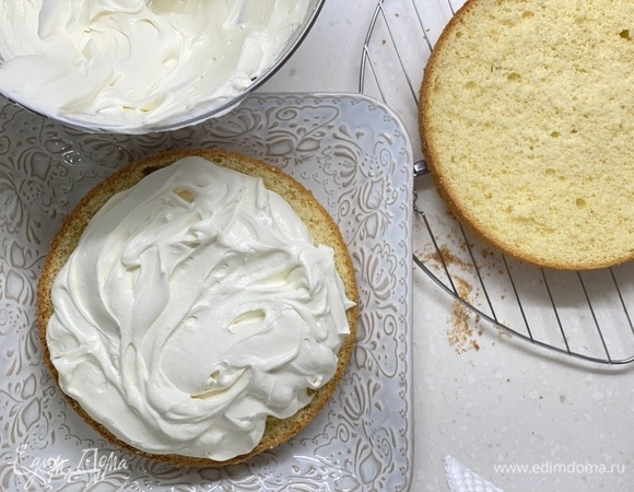 Взбить охлажденный крем в пышную массу миксером. Выложить на 1 корж (немного оставить на верх и бока), накрыть вторым. Обмазать остатками бока и верх торта.