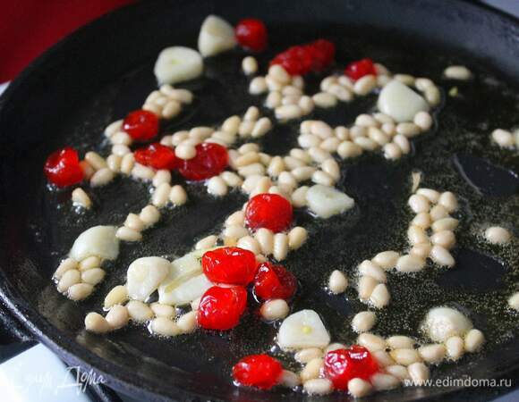 В сковороду кладем кусочек сливочного масла, нарезаем чеснок и добавляем туда же. Засыпаем в сковороду вишню и кедровые орешки, обжариваем на среднем огне несколько минут, пока орехи не подрумянятся.