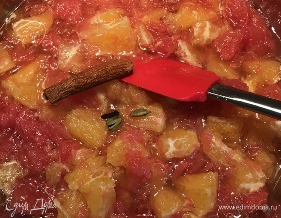 Переложить нарезанные цитрусы в сковороду с толстым дном, добавить корицу, гвоздику, кардамон и поставить на медленный огонь.