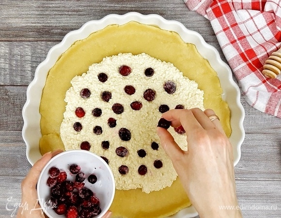 Тесто раскатываем в круг диаметром 35 см. Выкладываем начинку, не доходя до края 5 см. Сверху раскладываем замороженную клюкву, утапливая ее.