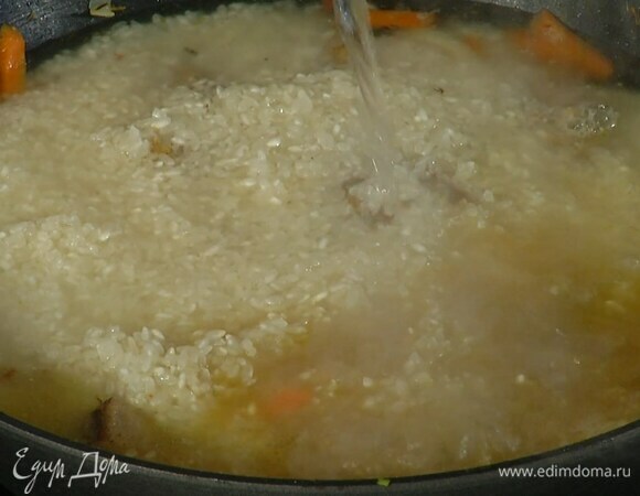 Рис промыть, всыпать в сковороду к мясу и, не перемешивая, равномерно распределить, затем влить кипяток, так чтобы рис был покрыт на 1–2 см.