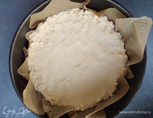 Форму диаметром 20–22 см застелить пергаментом. На дно выложить одну часть крошки, немного придавать пальцами.