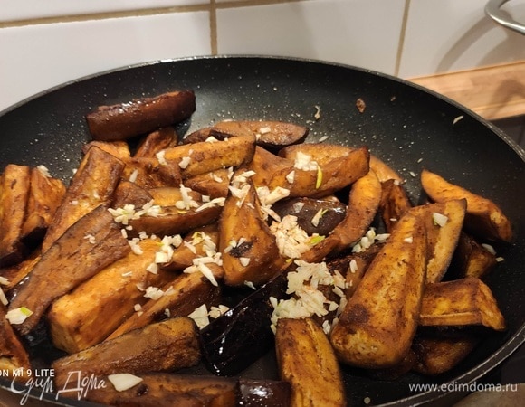 Затем посыпать мелко нарезанным чесноком и отправить в духовку еще на 5 минут. Можно по желанию превратить чеснок в кашицу и смешать с баклажанами. Противень достать из духовки, дать баклажанам чуть остыть.