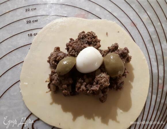 Разделите тесто на 16 частей и раскатайте каждую часть в блинчик толщиной примерно 2 мм. В центр положите начинку, сверху — 1–2 оливки и дольку яйца (у меня на фото целое перепелиное яйцо). Увлажните края теста, защипните края.