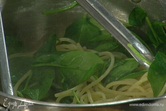 Спагетти вернуть в кастрюлю, поставить на небольшой огонь, добавить шпинат, влить немного воды, в которой варились макароны, и перемешать, чтобы шпинат привял.