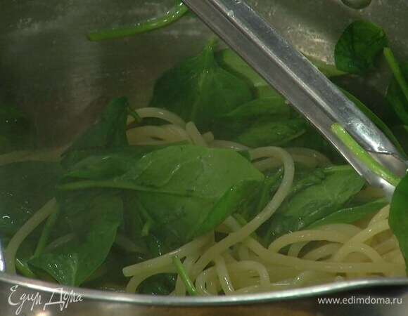 Спагетти вернуть в кастрюлю, поставить на небольшой огонь, добавить шпинат, влить немного воды, в которой варились макароны, и перемешать, чтобы шпинат привял.