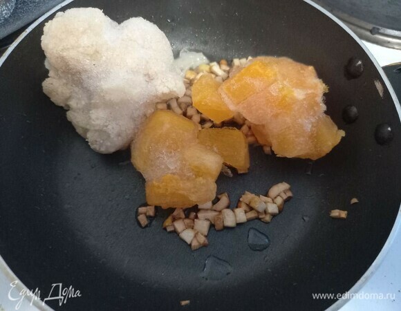 Добавить к обжаренному чесноку тыкву и цветную капусту, закрыть крышкой.