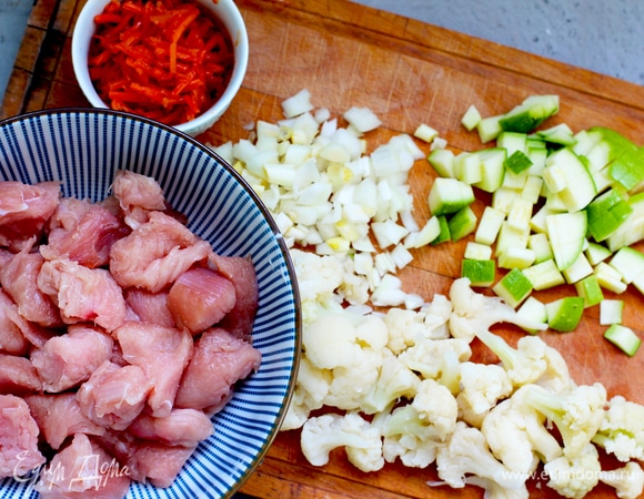 Лук, кабачок и индейку нарежьте кубиками. Чеснок измельчите. Если у вас будет острая морковь, то чеснок можно опустить. Цветную капусту разберите на соцветия и отварите 2 минуты в кипящей подсоленной воде.