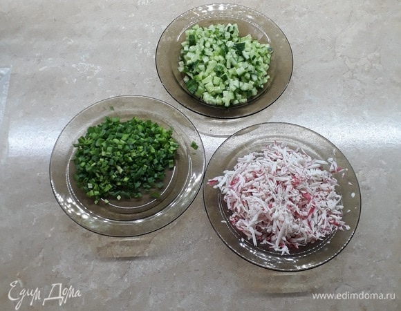 Приготовить начинку: потереть на крупной терке крабовое мясо или палочки, огурцы нарезать мелкими кубиками со стороной 5 мм, лук мелко нарезать.