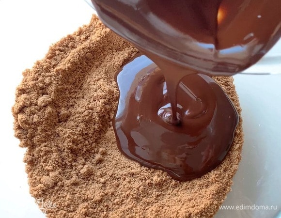 Влейте шоколад к печенью, перемешайте. Дно формы застелите пергаментом и выложите шоколадную основу.