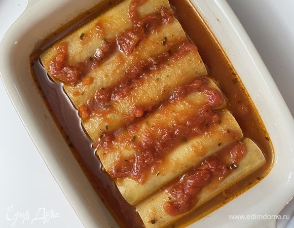 Духовку разогреть до 200°C. В оставшийся соус долить 100 мл горячей воды, перемешать. Влить немного соуса на дно формы. Разложить в один слой начиненные трубочки, залить оставшимся соусом.