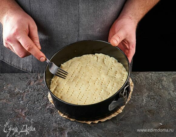 Замесите тесто. Оно получится очень нежным и влажным. Выложите тесто с разъемную форму. Равномерно распределите его по дну. Вилкой проколите дырочки в тесте.