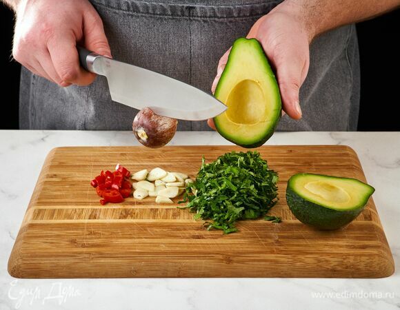Авокадо разрежьте пополам и удалите косточку, чили, чеснок и кинзу измельчите.