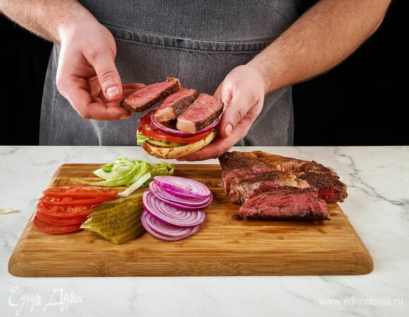 Мясо нарежьте на тонкие кусочки. Соберите бургеры. Положите поочередно все овощи, ломтики стейка и сыр. Накройте второй половиной булочки.