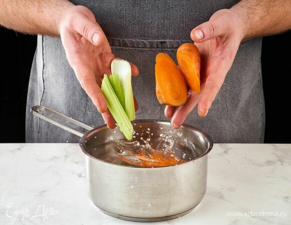 Морковь и сельдерей крупно нарежьте. Положите в кастрюлю с горячей водой.