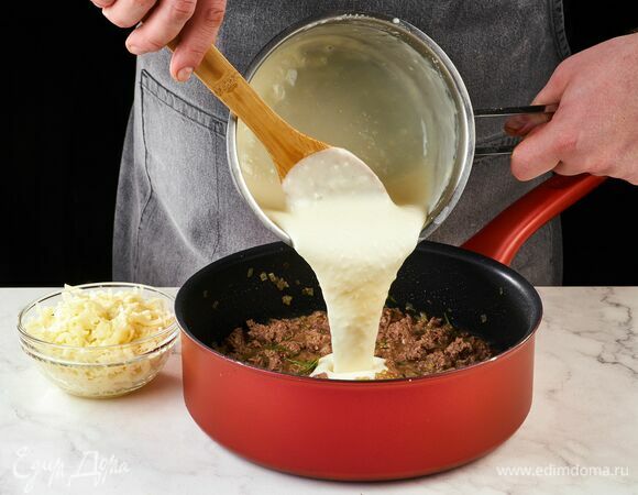 Влейте половину белого соуса и добавьте 250 г тертой моцареллы, перемешайте. Дайте начинке остыть.