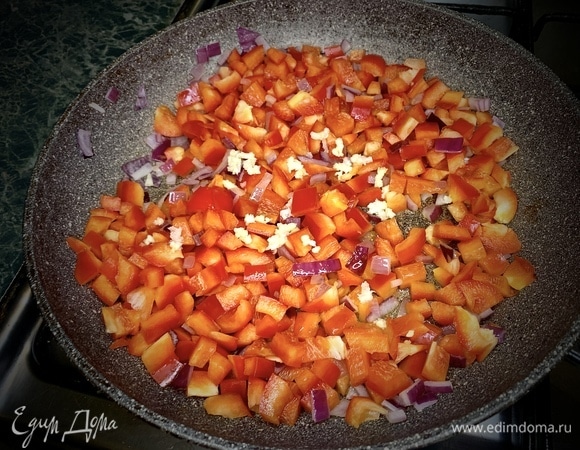 Обжариваем лук 2 минуты. Добавляем паприку и измельченный чеснок. Жарим 5 минут, постоянно помешивая.