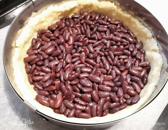 Затем всыпьте фасоль и поставьте в разогретую до 180°C духовку на 20 минут. Выньте тесто и удалите фасоль.