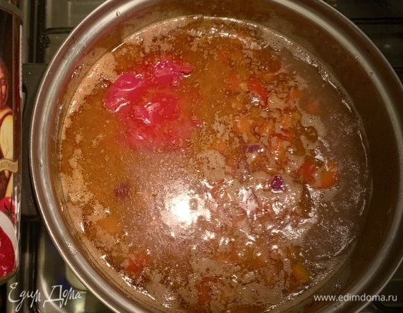 Перемещаем фарш в кастрюлю, заливаем бульоном. Добавляем помидоры, томатную пасту, майоран и сахар. Доводим до кипения, уменьшаем огонь, накрываем крышкой и варим 20 мин.