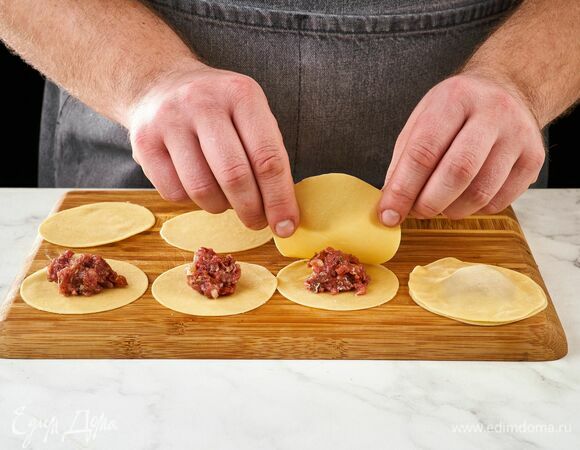Слепите равиоли. На одну заготовку положите немного фарша, накройте второй, аккуратно прижмите края. Повторите процедуру со всеми заготовками.