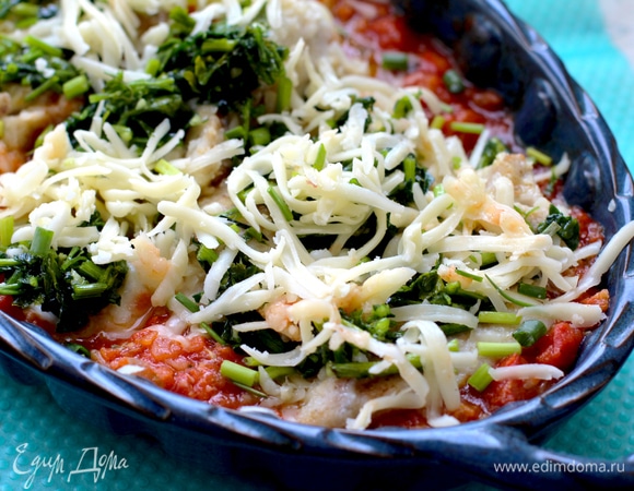 Вылить соус в форму для запекания. Выложить кусочки минтая, вдавливая их в соус. Минтай сверху покрыть базиликом в оливковом масле. Поверх выложить немного тертой моцареллы и нашинкованный зеленый лук (нашинковать одно перо или совсем убрать).