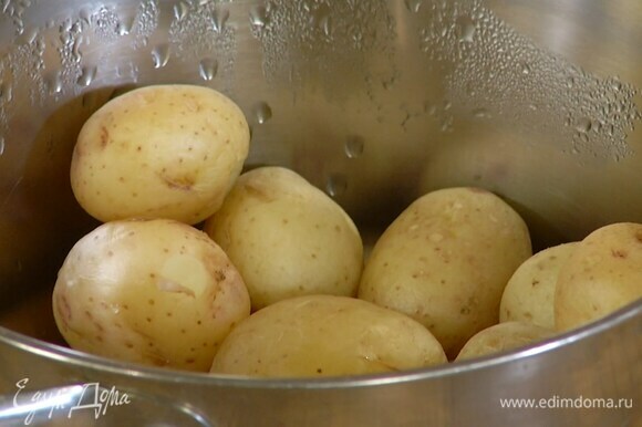 Вскипятить воду в кастрюле, опустить в нее вымытый картофель и отваривать целиком 10 минут, затем разрезать пополам.