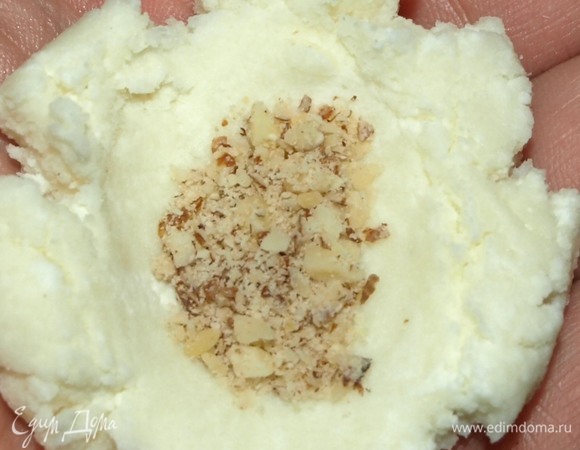 Отрываем от массы кусочек размером с грецкий орех и делаем лепешку. Кладем в середину лепешки 0,5 кофейной ложки молотого миндаля. Скатываем шарик. При необходимости руки слегка смочить водой.