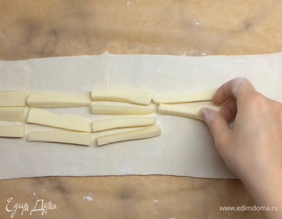 Второй лист теста из упаковки (250 г) делим тоже на два кусочка. Один откладываем, он нам не понадобится. Второй кусочек раскатываем так же, как и предыдущие, и выкладываем брусочки сыра в серединку, хорошо скрепляем края.