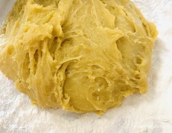 Горячее тесто выложить на стол, посыпанный мукой, и, пока оно не остыло, замесить с оставшейся мукой.