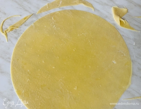 Каждую часть раскатать максимально тонко (как лаваш) в круг диаметром 26 см. По всему периметру сделать проколы вилкой. Неровные края теста от каждого кусочка отрезать и испечь в конце.