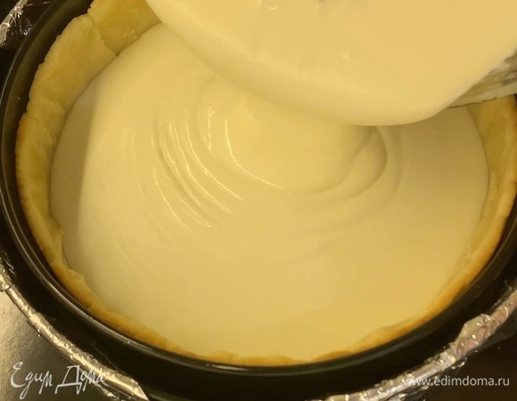 Начинку вылейте в охлажденную основу. Форму с чизкейком поставьте в другую (большего диаметра) и всю конструкцию поставьте в глубокий противень.