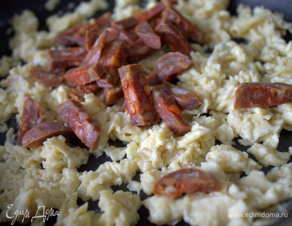 Нарезать несколько колечек чоризо соломкой и пересыпать в омлет. Подержать немного на огне вместе.