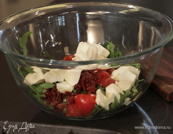 Черри нарежьте дольками, 30 грамм вяленых томатов — тонкими ломтиками, моцареллу — крупными кусочками. Смешайте ингредиенты в глубокой миске вместе с руколой. 
