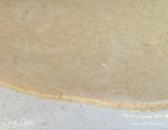 Подошедшее тесто выложить на присыпанную пшеничной мукой рабочую поверхность и раскатать в тонкий пласт.