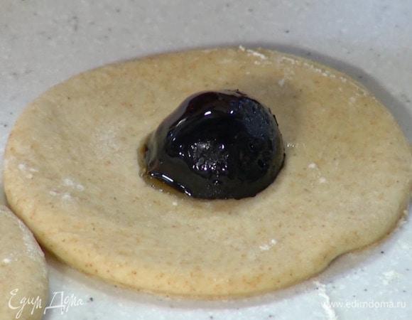 Вырезать из теста кружки, в центр каждого выложить половинки грецких орехов из варенья, соединить и защипать края, сформировав шарики.