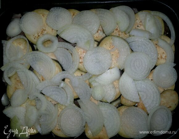 Выложить лук на баклажаны.