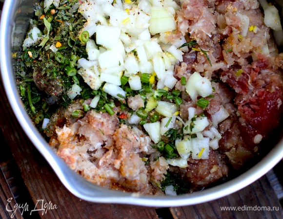 В фарш добавить мелко нарезанный репчатый лук, чеснок, пропущенный через пресс, приправы, соль и 2 ст. л. кефира для сочности. Все перемешать.