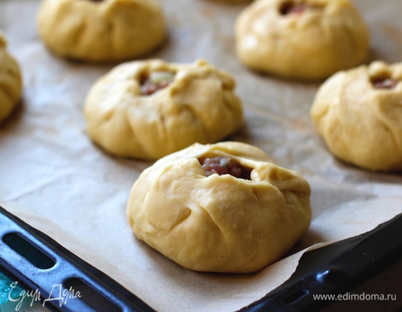 Уложить заготовки на противень, застеленной бумагой для выпечки. Смазать верх желтком, взболтанным с 1 ст. л. жирных сливок.