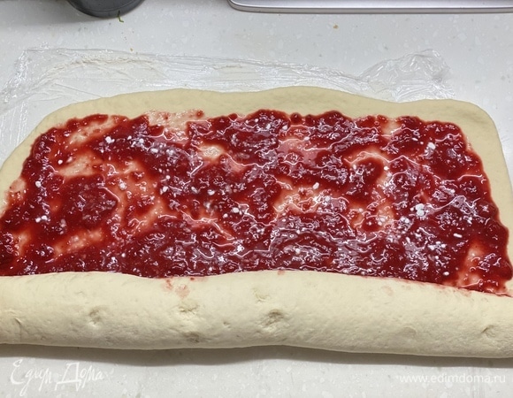 Готовое тесто раскатать в пласт толщиной не более 1 см. Распределить сверху клубничную начинку. Скрутить в рулет.
