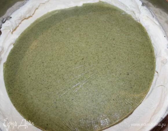 Для монтажа отрегулируйте кондитерский круг на 20 см в диаметре и натяните пищевую пленку. Положите круг пленкой на дно и выложите часть мусса. Разровняйте его, затем в центр уложите вставку из чая матча.