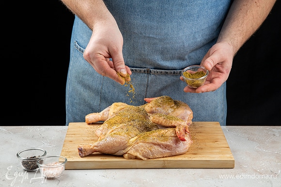 Цыпленка разрежьте по линии грудки. Смешайте хмели-сунели, соль и перец. Натрите этой смесью цыпленка со всех сторон.