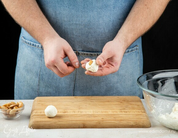Смочите руки холодной водой. Возьмите миндальный орех и сформируйте вокруг него творожно-медовый шарик.