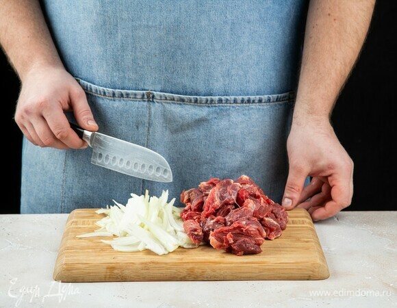 Нарежьте мясо средними кубиками. Лук нарежьте полукольцами.