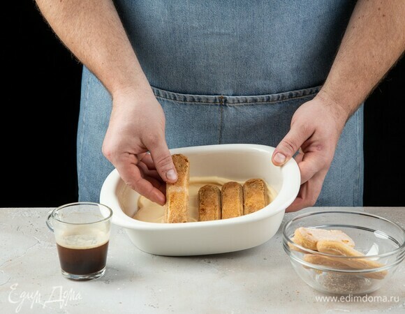 По дну формы распределите слой крема. Печенье окуните в кофе, выложите на крем.